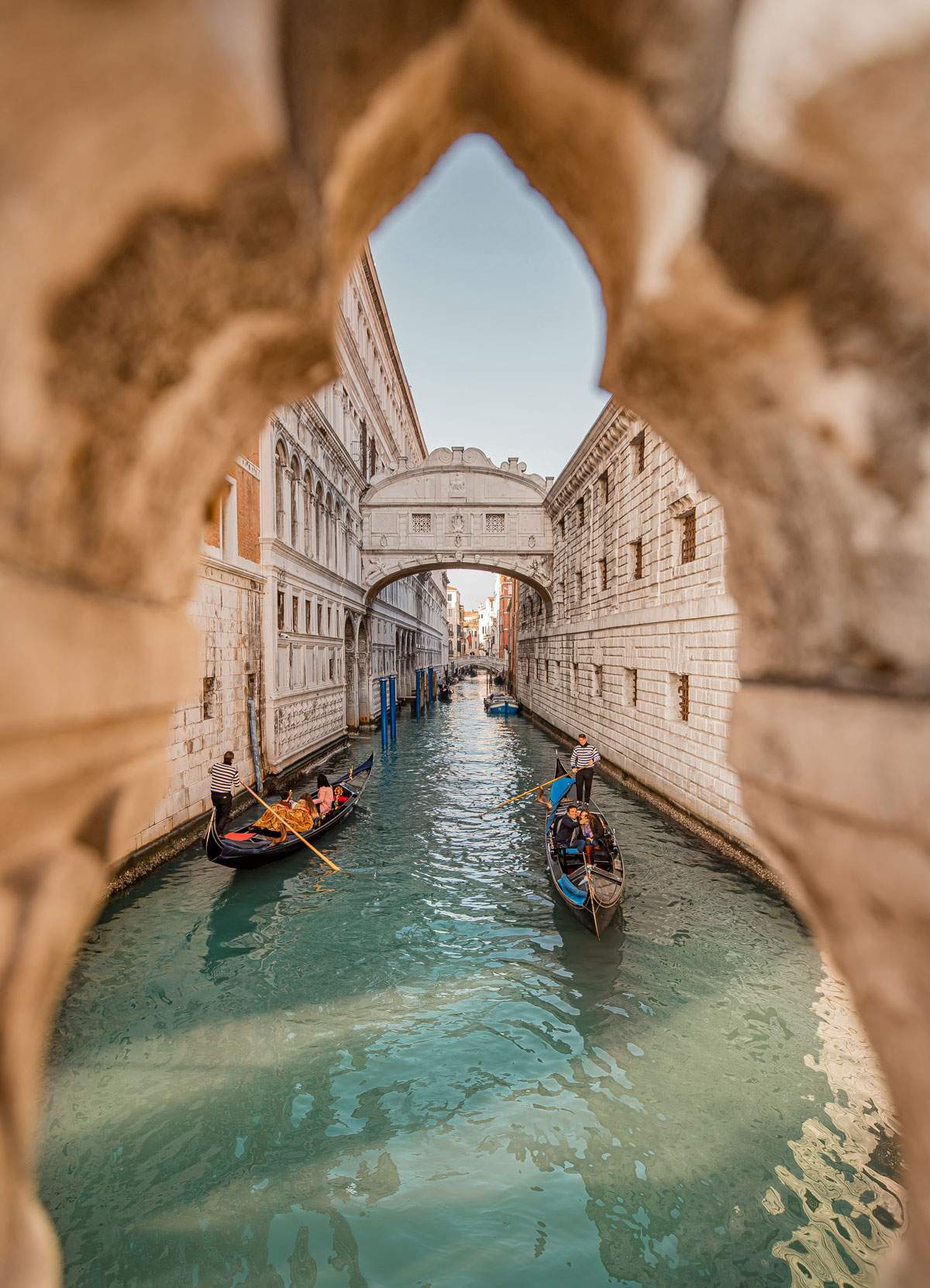 two gondolas floating down a canal with a view of theBridge of Sighs