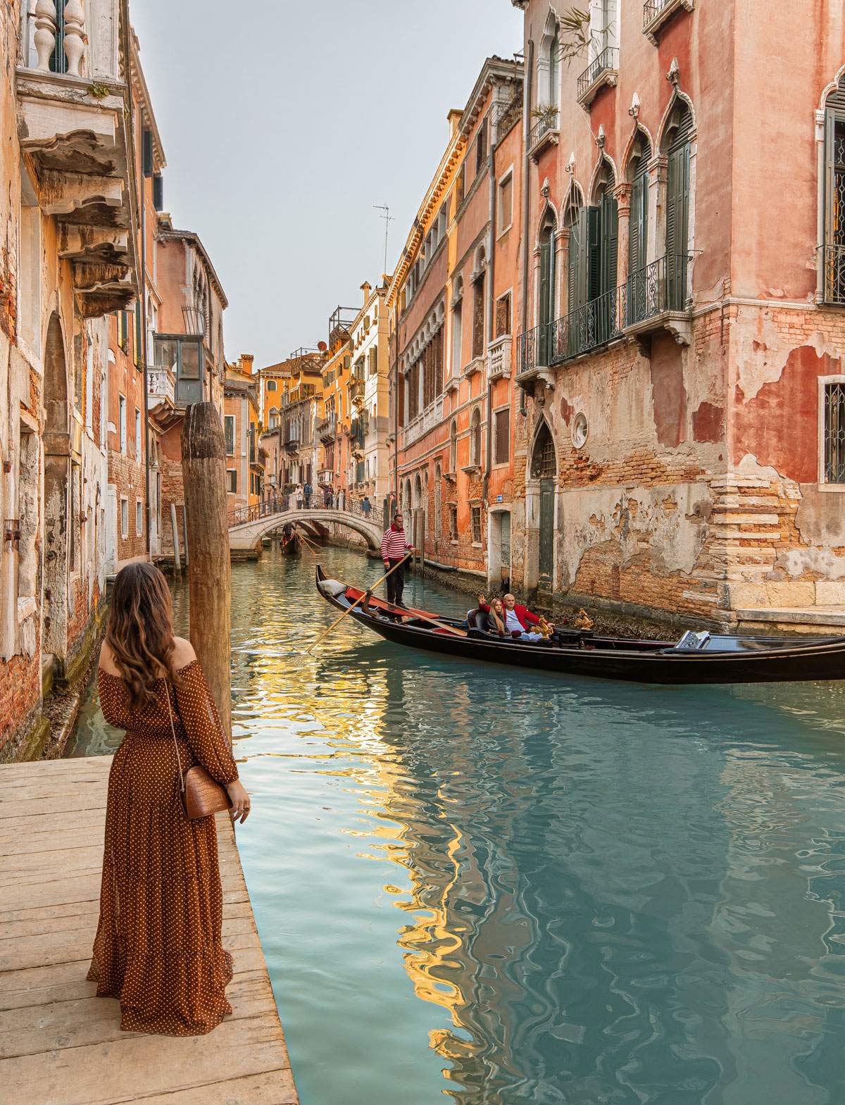 Kelsey standing next to canal in venice as a gondola floats by