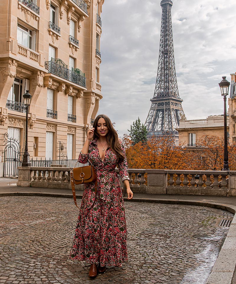 kelsey standing on cobblestone street with view of eiffel tower in background and orange autumn trees
