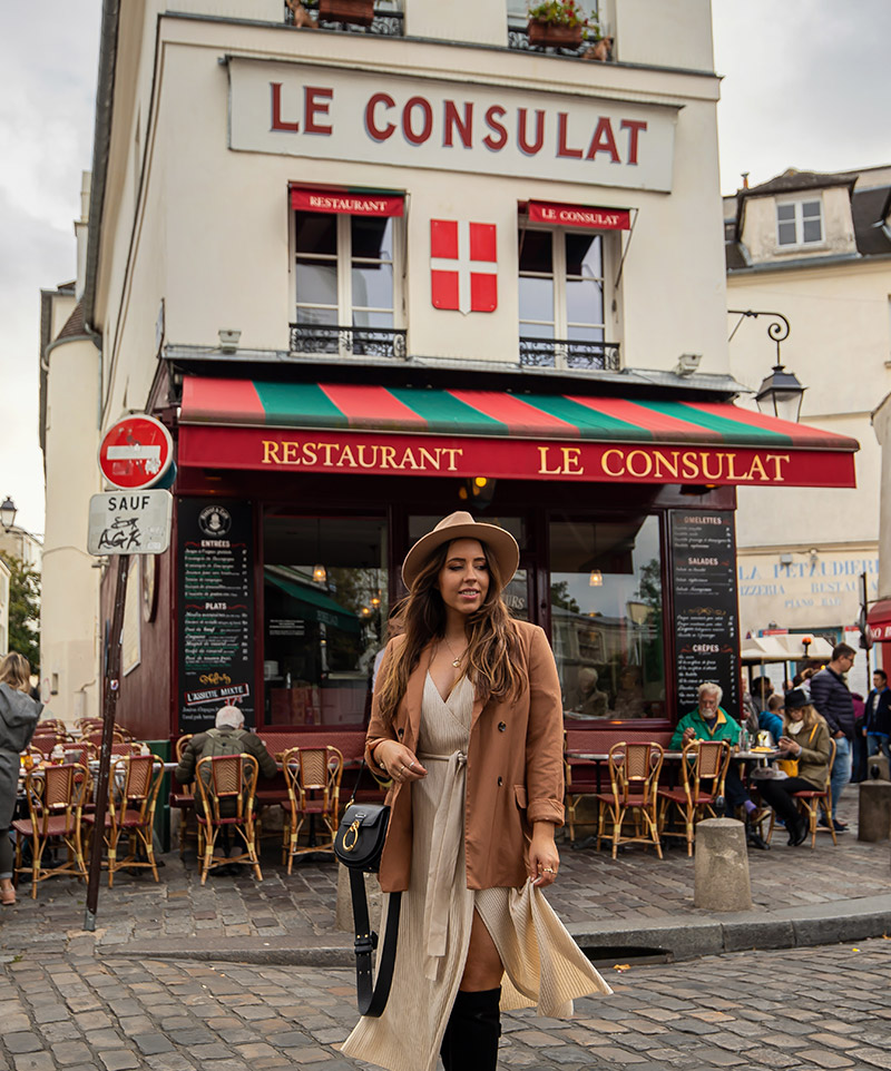 Kelsey standing outside Le Consulat restaurant with red and green decorations