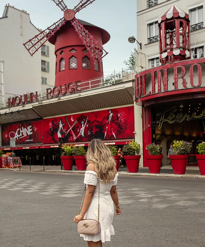 kelsey in front of the Moulin Rouge building with its red windmill, kelsey is wearing a white summery dress