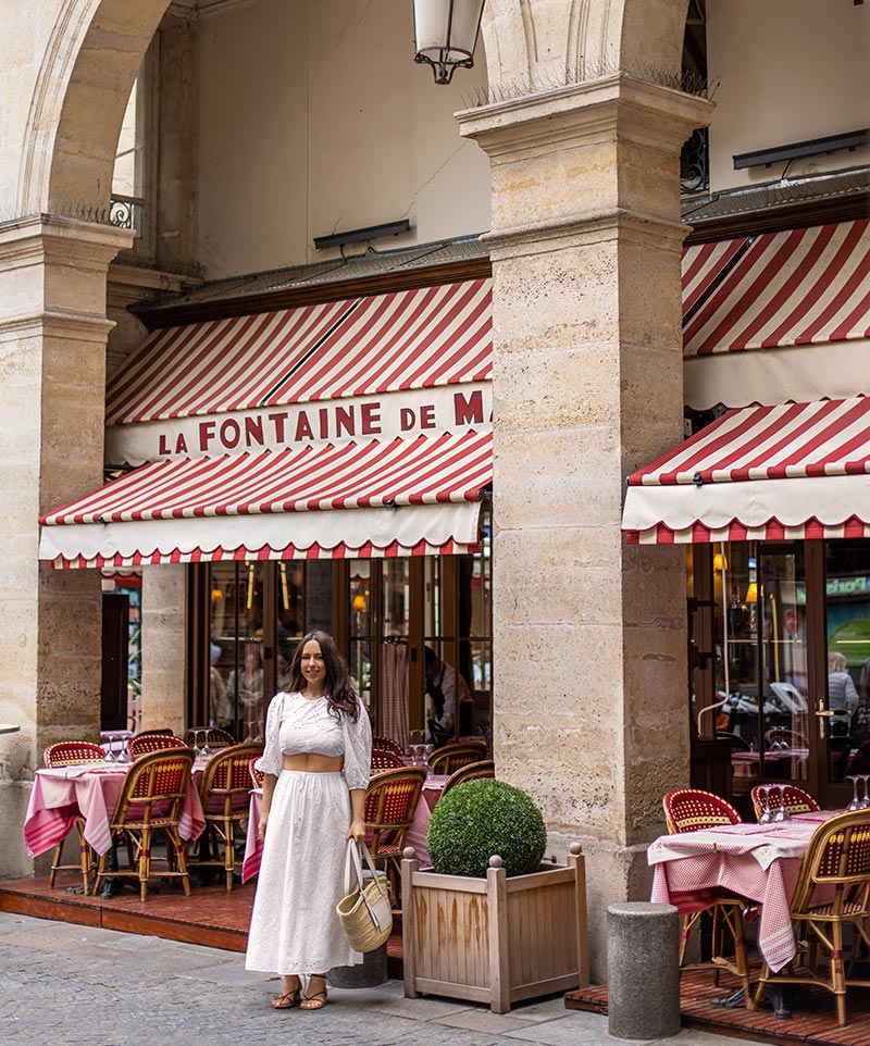 woman standing in front of french bistro style restaurant