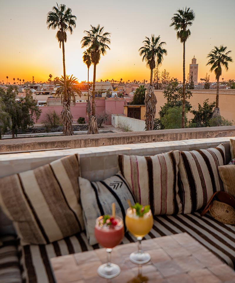 two cocktails on a table with a sunset view and palm trees