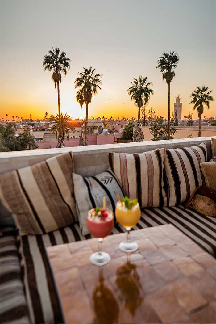 two cocktails on a table with a sunset view and palm trees