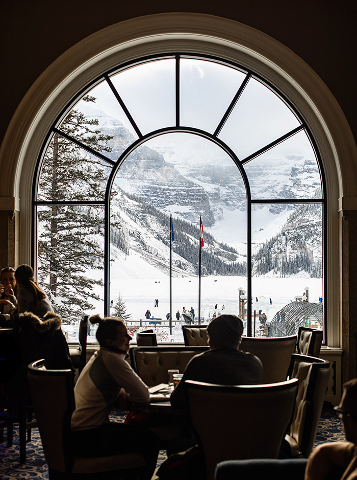 A big arched window with a view of snowcapped mountains outside. 