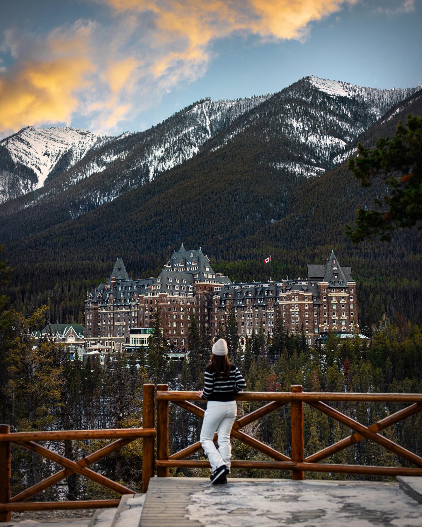 Kelsey stands at a wooden fence with a view of Fairmont Banff Springs hotel in the background