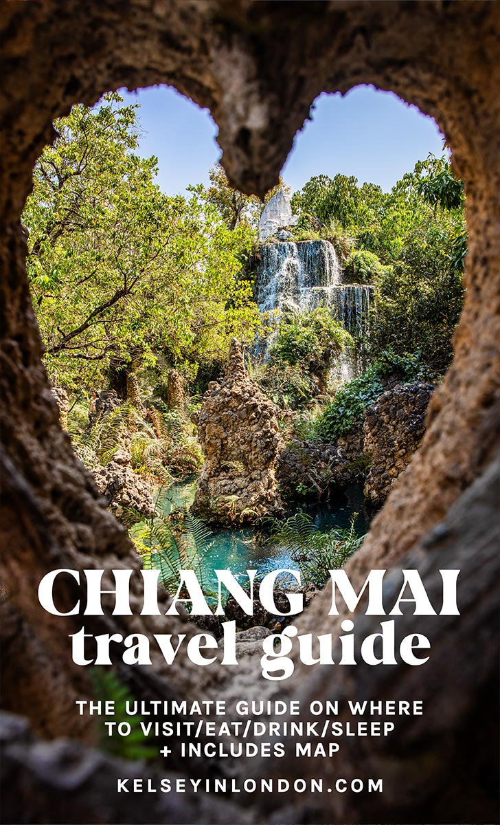 A Pinterest-style travel guide cover for Chiang Mai, Thailand, featuring a stunning waterfall framed by a heart-shaped rock opening. The cascading water flows into a turquoise pool surrounded by lush greenery and jagged rock formations, creating a magical, serene atmosphere. Bold white text overlays the image, reading "Chiang Mai Travel Guide – The Ultimate Guide on Where to Visit/Eat/Drink/Sleep + Includes Map," with "KelseyInLondon.com" displayed at the bottom.